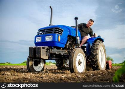 A farmer on a tractor cleans the field after harvest. Preparation of land for future planting new crop. Intensive land use. Milling soil, loosening ground before cutting rows. Farming, agriculture.