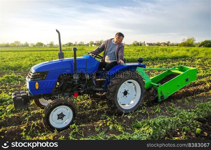 A farmer on a tractor digs potatoes with a digger. The use of modern technology on the farm. Free people from heavy land work. Farming and farmland. Countryside. Food production