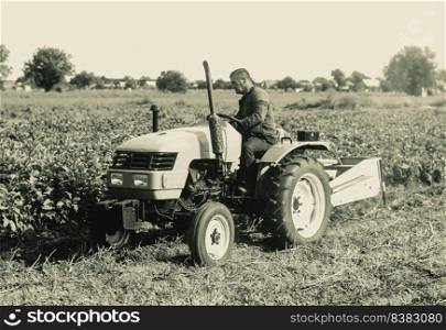 A farmer on a tractor is working on a farm field. Agroindustry and agribusiness. Agricultural sector of the economy. Plant food production. Machinery and equipment.