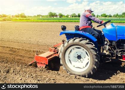 A farmer on a tractor works the field with a shredder in preparation for planting a new crop. Loosens, grind and mix soil. Moldboard loosening surface. Farming, agriculture. Plowing.