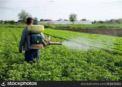 A farmer sprays chemicals on a potato plantation field. Increased harvest. Control of use of chemicals growing food. Protection of cultivated plants from insects and fungal infections.