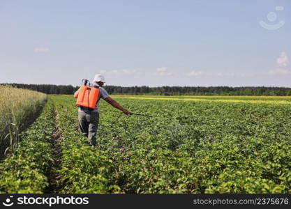 A farmer with a mist sprayer treats the potato plantation from pests and fungus infection. Use chemicals in agriculture. Agriculture and agribusiness. Harvest processing. Protection and care.. A farmer with a mist sprayer treats the potato plantation from pests and fungus infection. Use chemicals in agriculture. Agriculture and agribusiness. Harvest processing. Protection and care