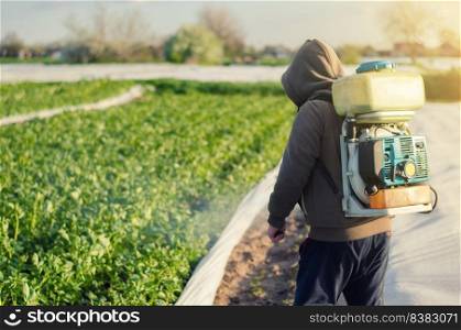 A farmer with a sprayer treats a potato plantation with a pest and fungus agent. Effective crop protection, environmental impact. Protection of cultivated plants from insects and fungal infections