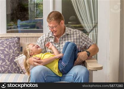 A father and daughter spending fun time together outside on the porch of their home.