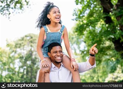A father and his daughter having fun and spending good time together while walking outdoors on the street.