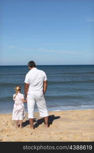 A father and his daughter looking at the sea.