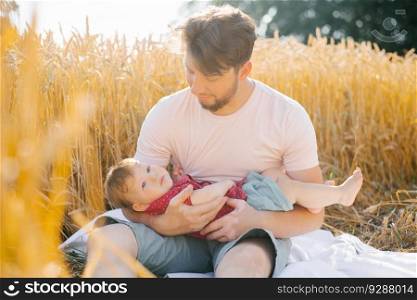 A father and his son have a rest outdoors in a field in summer
