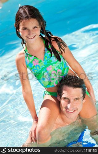 A father having fun with his daughter on his shoulders in a swimming pool