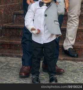 A father helps his son get dressed. Stylish little boy with broken arm with plaster. 