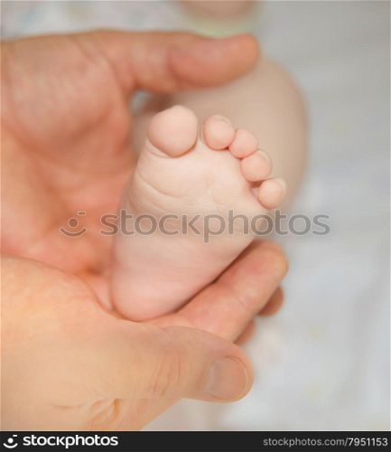 A father hold the the foot of his new born son