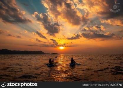 A female and a male sailing with canoes close to each other at sunset. Female and a male sailing with canoes close to each other at sunset
