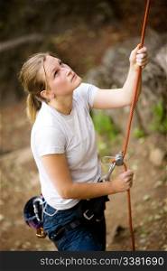 A female belaying a male on a steep rock face. Shallow depth of field has been used to isolated the belayer, with focus on the eyes and head.