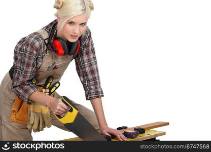 A female carpenter sawing.