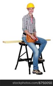 A female carpenter sitting on a workwrench.