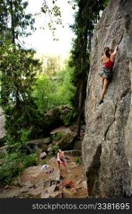 A female climber, climbing using a top rope on a steep rock face (crag)