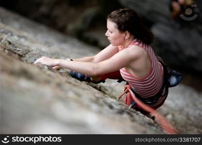 A female climber on a steep rock face. Shallow depth of field is used to isolated the climber.