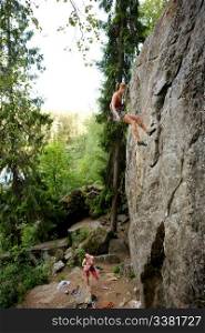 A female climber, repelling down a steep rock face (crag)