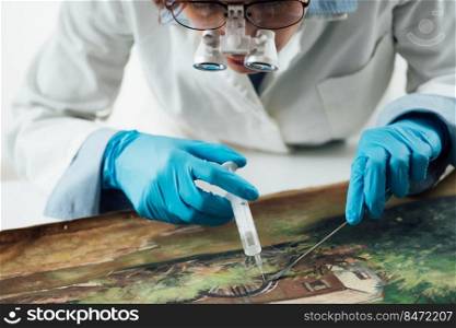 A female conservator with magnifying goggles repairing damages on an oil painting canvas.. Oil Painting Restoration