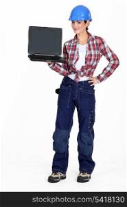 A female construction worker holding a laptop.