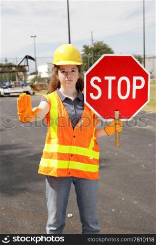 A female construction worker holding a stop sign.
