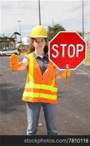 A female construction worker holding a stop sign.