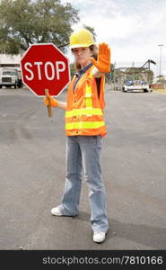 A female construction worker holding a stop sign. Full body view.