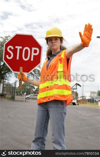 A female construction worker stopping traffic.