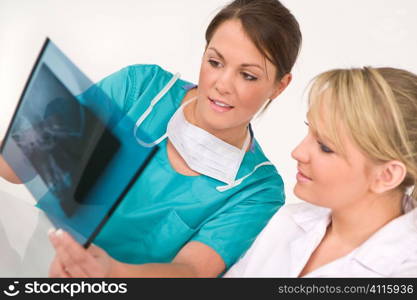 A female doctor and her nursing colleague examining an X-ray of a human skull