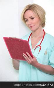 A female doctor taking notes on a clipboard.