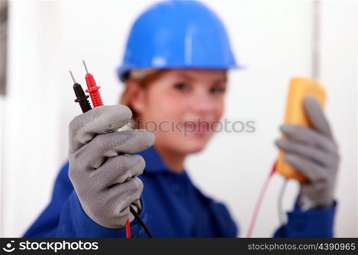 A female electrician holding a voltmeter.