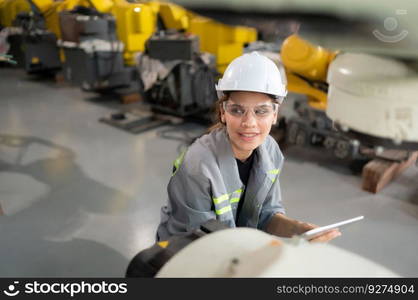 A female engineer installs a program on a robotics arm in a robot warehouse. And test the operation before sending the machine to the customer.