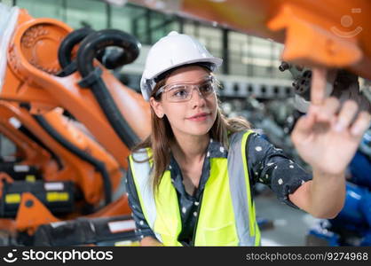 A female engineer installs a program on a robotics arm in a robot warehouse. And test the operation before sending the machine to the customer.
