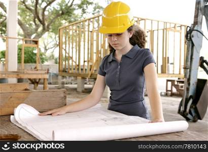 A female engineering student on the job site reviewing blueprints.