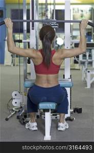 A female fitness instructor demonstrates a lat pulldown