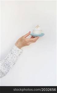 A female hand holds a delicious cupcake, congratulations on a happy birthday. Place for an inscription. A female hand holds a delicious cupcake, congratulations on a happy birthday. Place for an inscription.