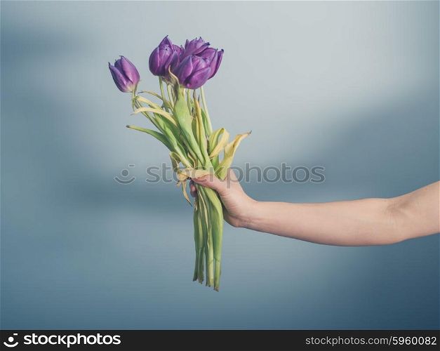 A female hand is holding a bouquet of dead flowers