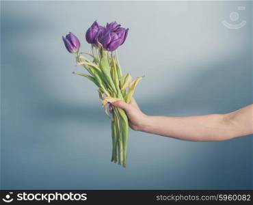 A female hand is holding a bouquet of dead flowers