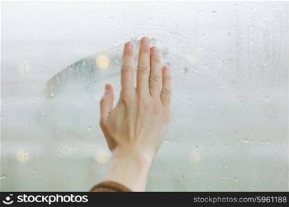 A female hand is wiping the dew of a window