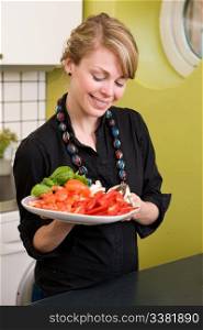 A female in the kitchen looking down on a tasty plate of vegetables - Shallow depth of feild is used to isolate the womans face.