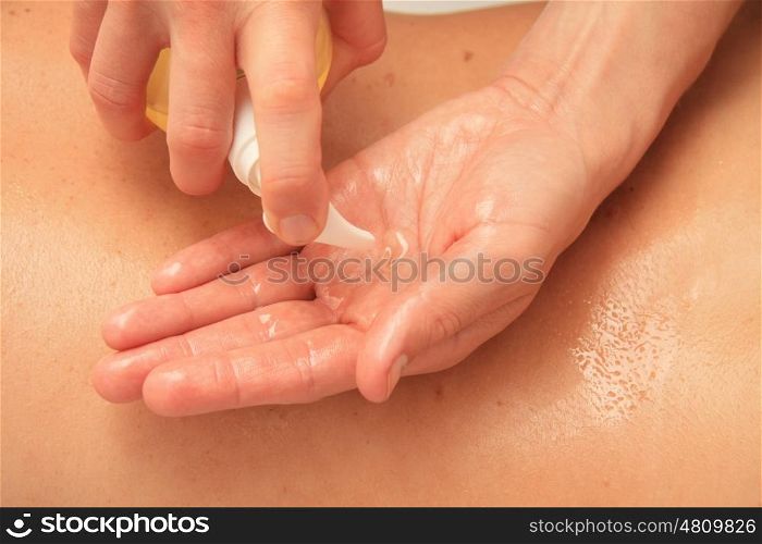 A female masseur preparing her hand with oil for a back massage