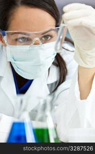 A female medical or scientific researcher or doctor looking at a liquid clear solution in a laboratory.