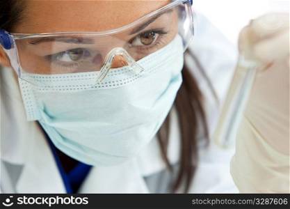 A female medical or scientific researcher or woman doctor looking at a clear solution in a laboratory.