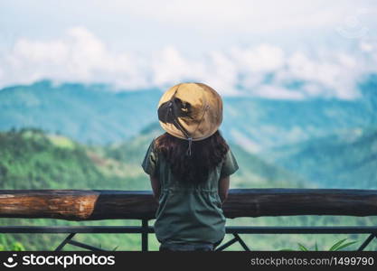 A female traveler sitting and looking at a beautiful green mountain on foggy day