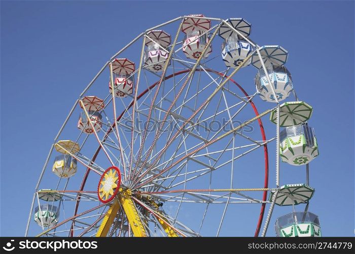 A Ferris wheel without passengers against clear blue sky.