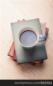 A few books with cup of coffee on wooden floor