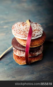 A few gingerbread cookies wrapped in red ribbon Happy Christmas on wooden table. Plain background. Portrait orientation