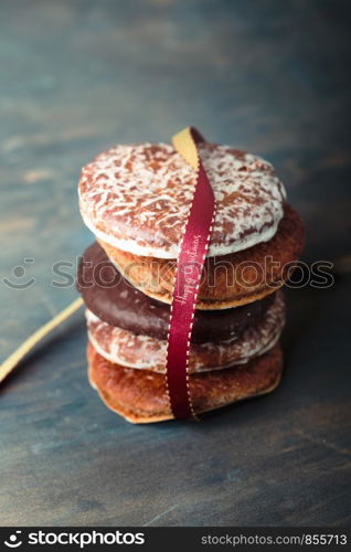 A few gingerbread cookies wrapped in red ribbon Happy Christmas on wooden table. Plain background. Portrait orientation