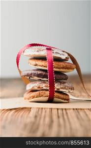 A few gingerbread cookies wrapped in red ribbon on wooden table. Plain background. Portrait orientation