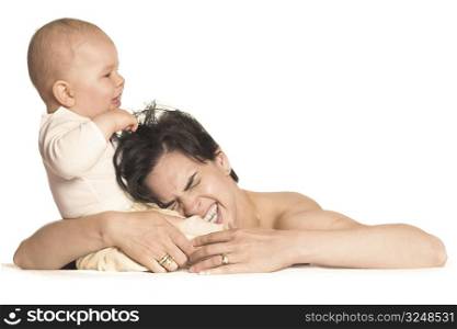 A few months old baby boy is pulling his mother&acute;s hair.