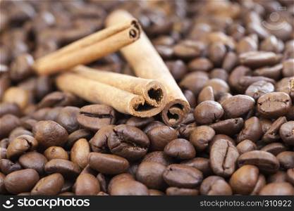 A few sticks of cinnamon lying on roasted fragrant coffee beans. Raw cinnamon coffee